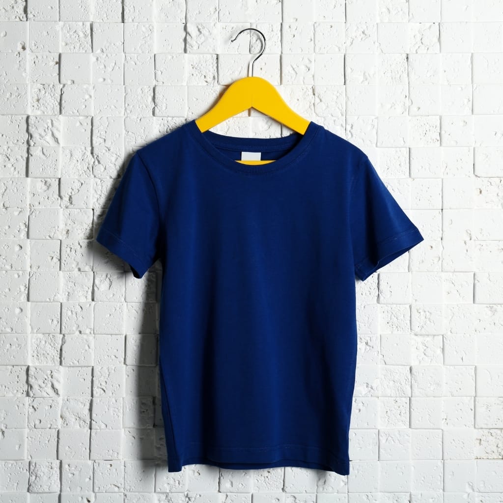 Royal blue t-shirt on a wooden hanger against a white textured tiled wall, front view.