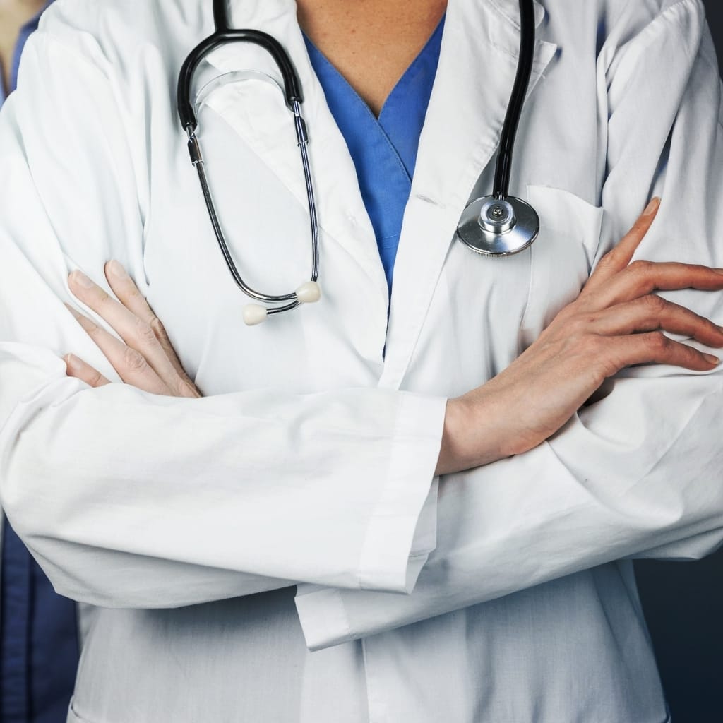 Close-up of a doctor in a white coat with a stethoscope around their neck, arms crossed.
