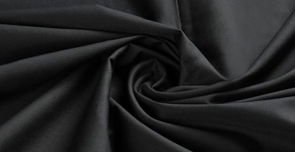 Close-up of black fabric with a smooth, matte texture, gathered in soft folds.