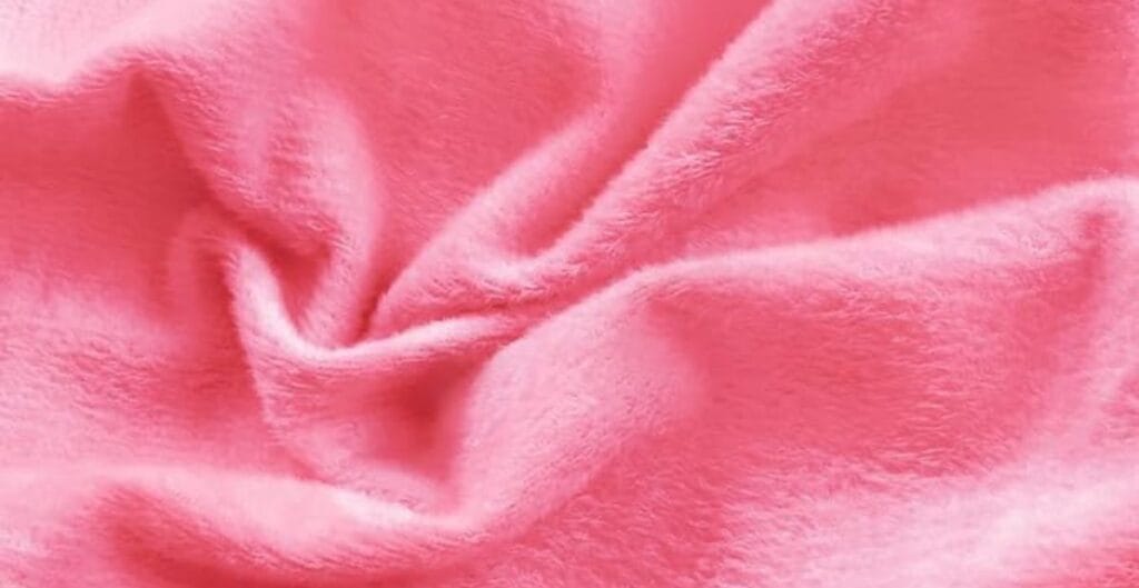 Soft pink fleece fabric with gentle folds and a plush texture.