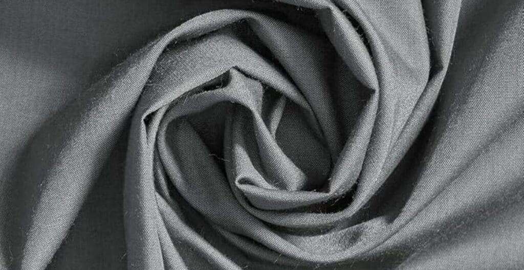 Close-up view of grey cotton fabric twisted into a swirl pattern.