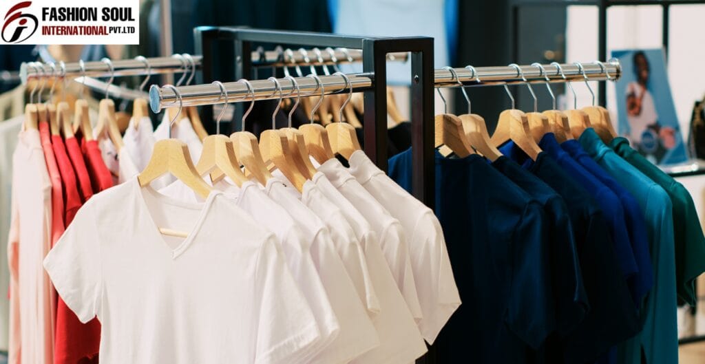 A clothing rack displaying neatly arranged white, navy, and teal shirts and tops, with a blurred background of a store interior.