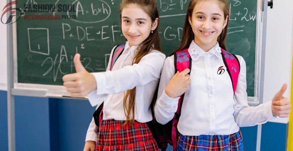 Two happy schoolgirls, dressed in white shirts and plaid skirts, standing in front of a chalkboard with scientific or mathematical formulas, giving thumbs-up gestures. They are wearing backpacks and smiling confidently.