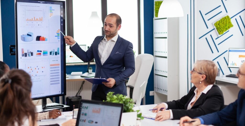 Close-up of customized MMA gloves with unique color scheme and personalized logo next to a mouthguard and headgear on a gym mat.