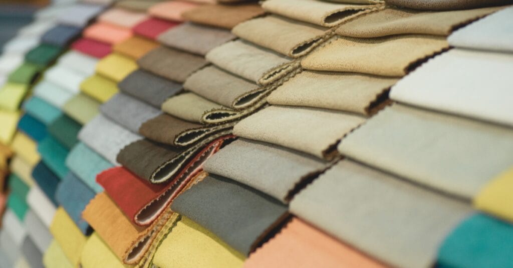 A wide-angle stack of folded fabric swatches in a rainbow of colors, arranged in diagonal rows.