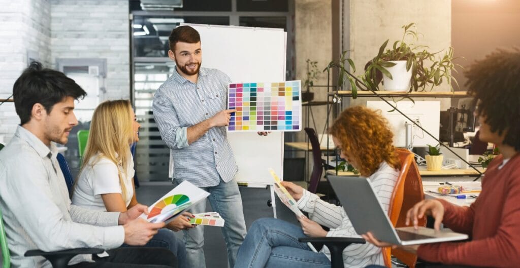 Graphic showing a designer researching a target audience with icons representing demographics, behaviors, and needs.