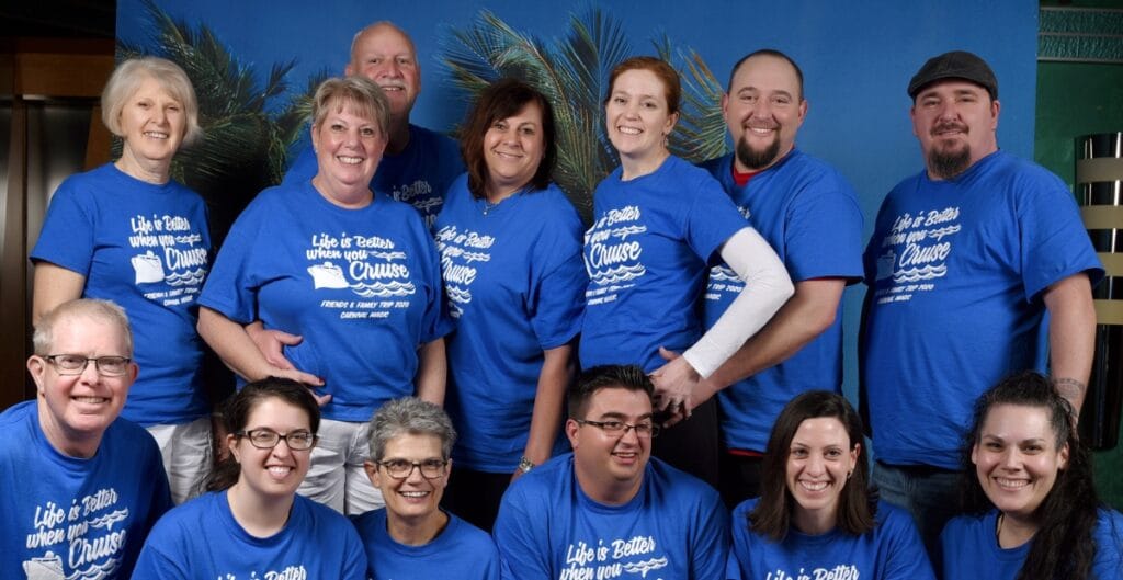 A diverse group of employees wearing customized organization T-shirts with personalized name badges and unique color accents. They are smiling and collaborating around a table, displaying a sense of belonging and personalization that enhances engagement.
