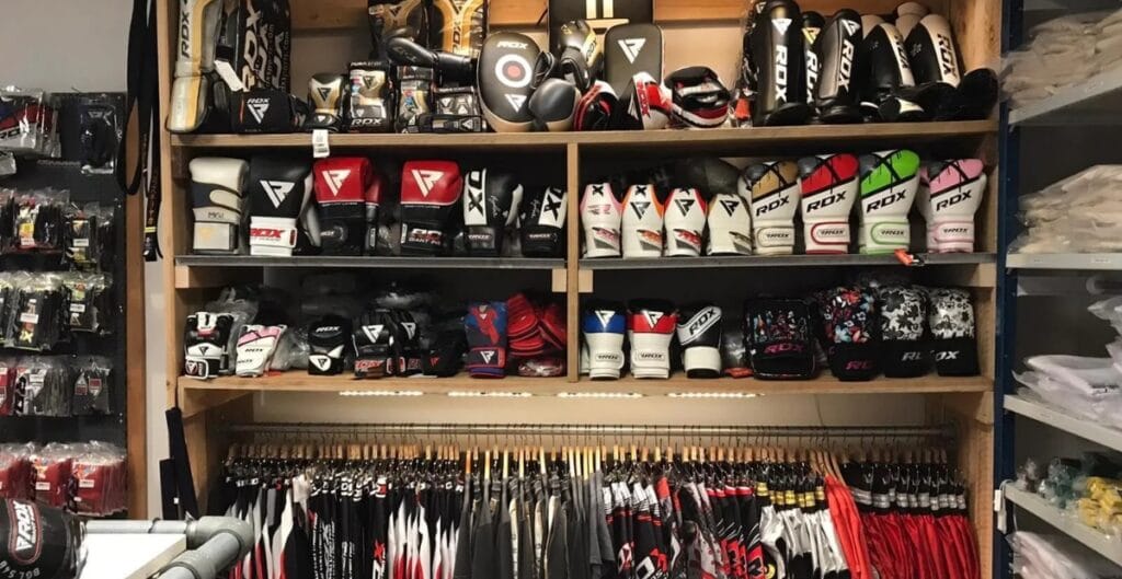 A procurement manager evaluating MMA gear from multiple suppliers, with comparison charts and product samples laid out on a table.