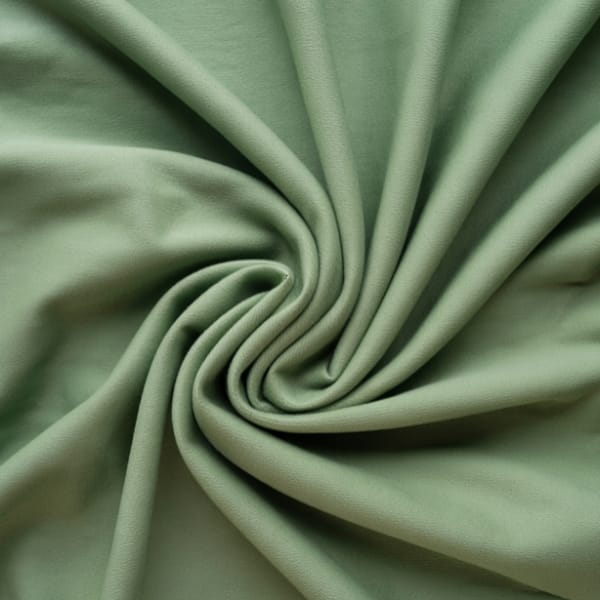 A close-up shot of soft, sage-green fabric twisted into a spiral, showing smooth folds and a subtle sheen.