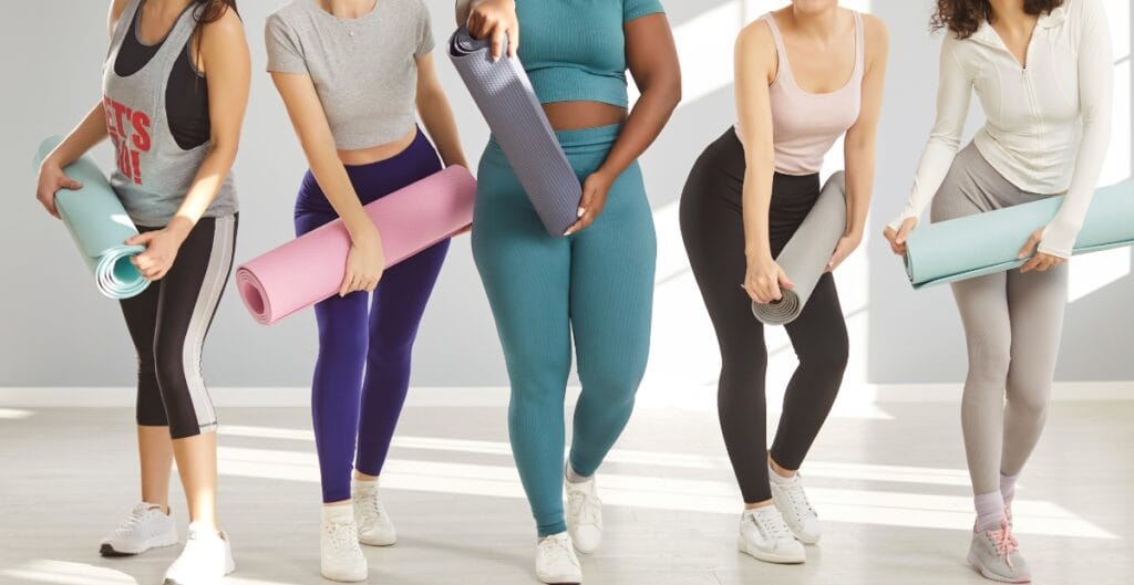 Group of women in various 3x yoga pants designs preparing for a yoga class