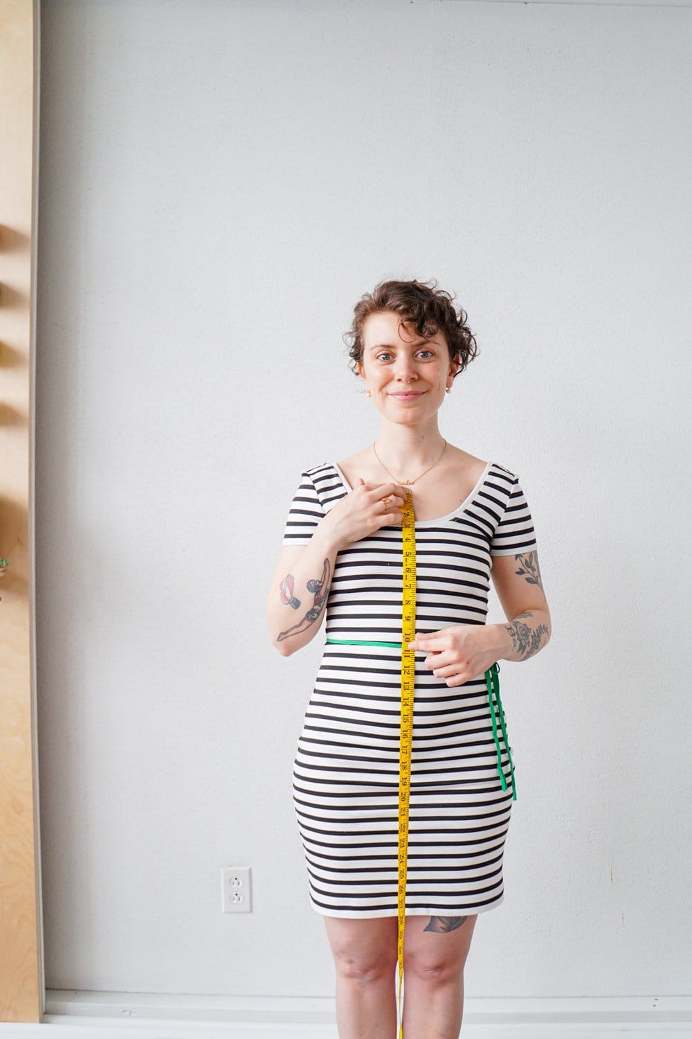 Woman measuring her waist with a tape measure for clothing size guide”