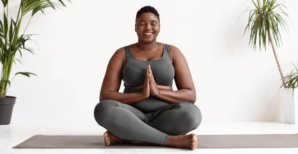 Confident plus size woman wearing a chic workout outfit stretches before her fitness routine, showing that exercise clothes can be both stylish and functional.