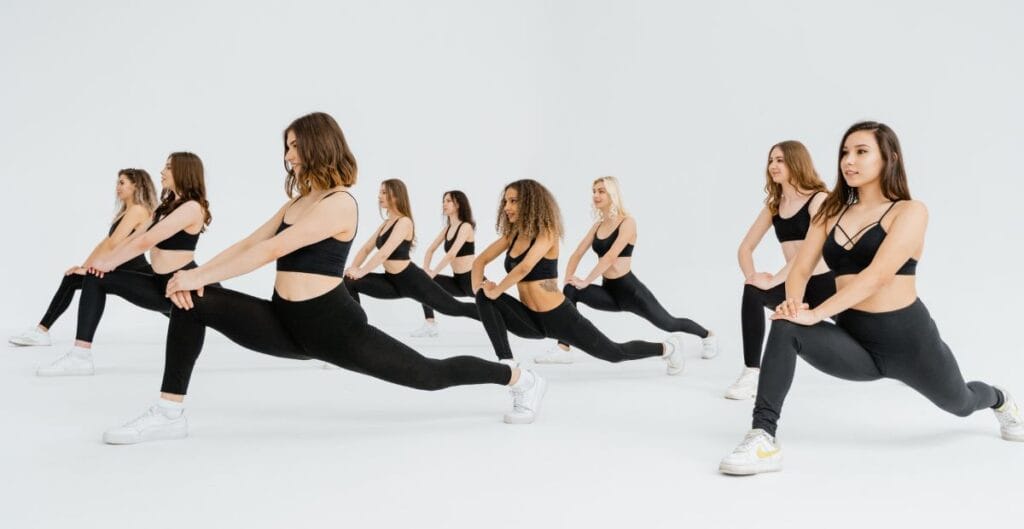 Group of women in workout leggings performing lunges together in a studio.