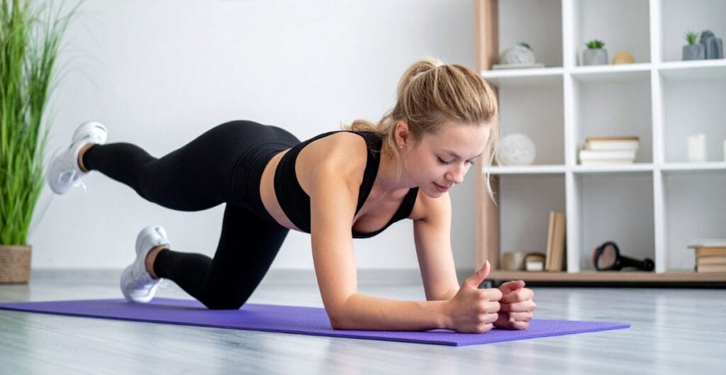Woman in black exercise leggings performing a plank pose on a purple mat, strengthening her core