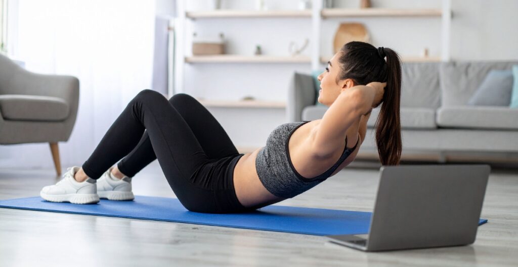 Woman doing ab exercises on a yoga mat in black exercise leggings, focusing on core strength.