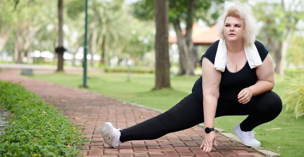 Curvy woman in black leggings stretching in a park, showing comfort and flexibility for active lifestyles