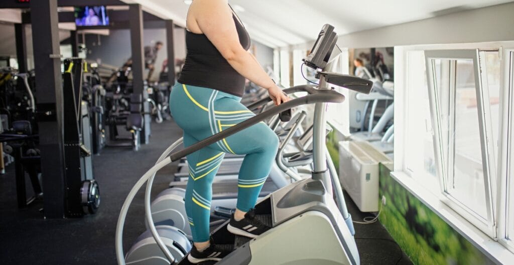 Stylish and Comfortable Cute Plus Size Leggings for Your Workout A person wearing cute plus size leggings on an elliptical trainer at the gym, showcasing comfort and style.