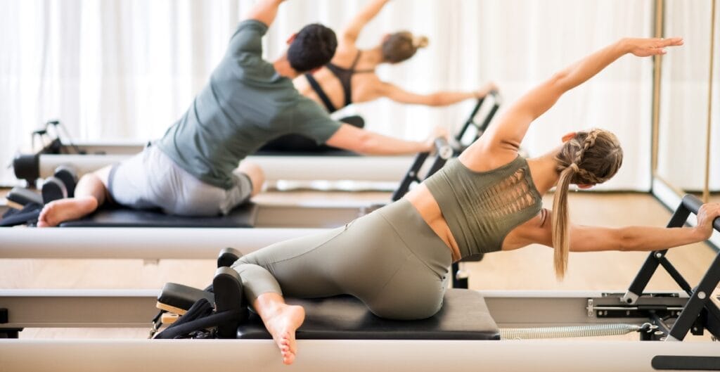 Two people performing Pilates exercises while wearing gym leggings for ladies, showcasing flexibility and support