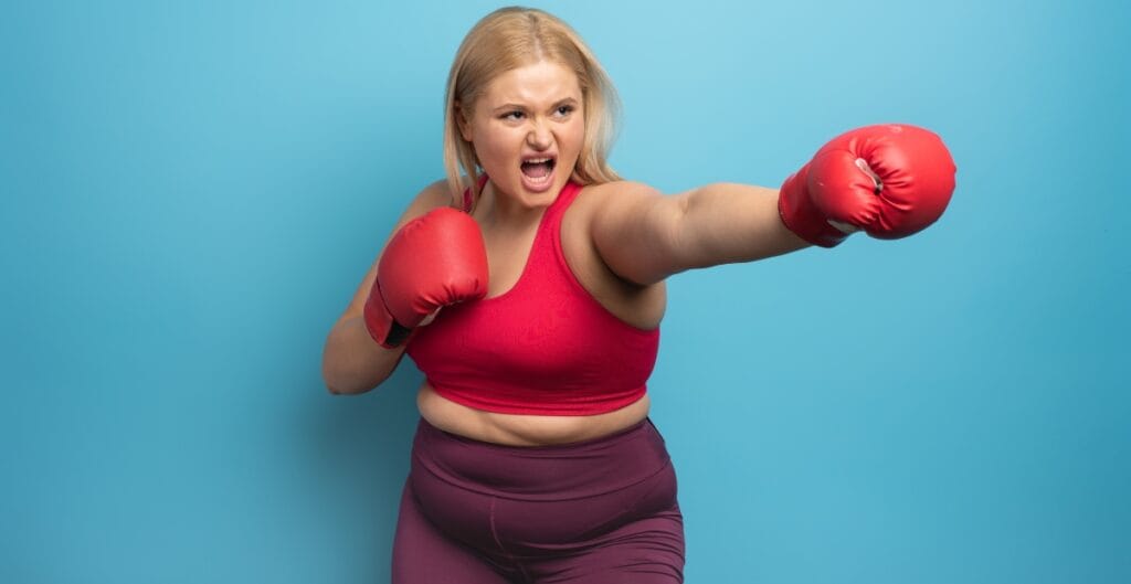 Woman in red boxing gloves, delivering a powerful punch, exuding confidence, highlighting activewear and the fit of plus size boxers