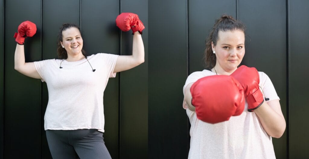 Woman wearing red boxing gloves, smiling, showcasing strength in a casual outfit, with focus on comfort and confidence