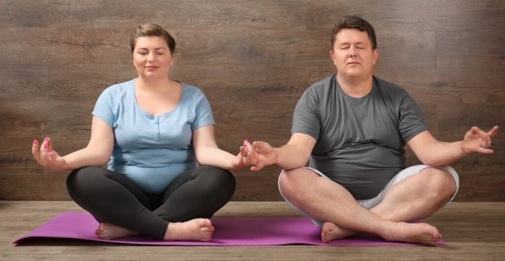 A couple doing yoga poses in plus size gym pants, demonstrating inclusivity and fitness for every body type