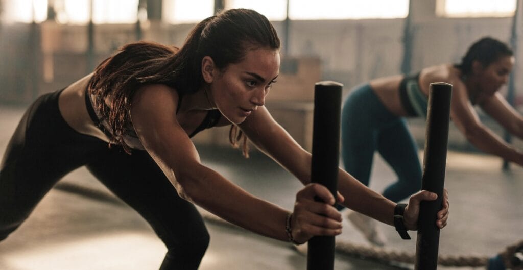 Woman pushing a sled in gym wearing black women's gym leggings