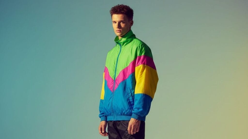 Model wearing retro sportswear with bold colorblock windbreaker in a minimal studio setting