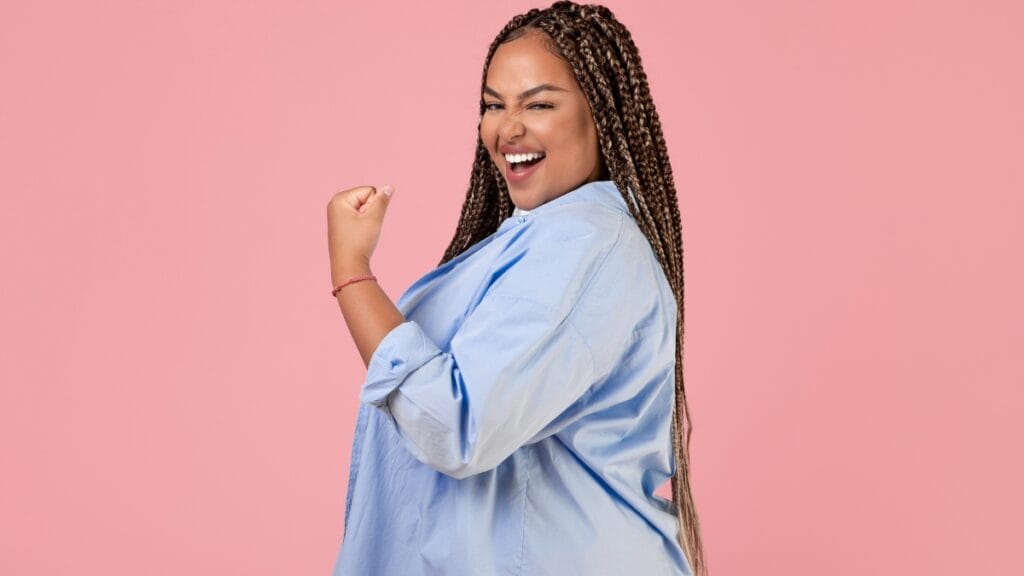 Curvy woman in a light blue plus size shirt, showing a strong, confident pose