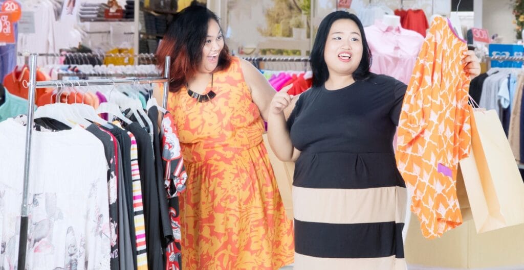 Two curvy women shopping for flattering dresses for curvy figures in bright prints and playful styles.