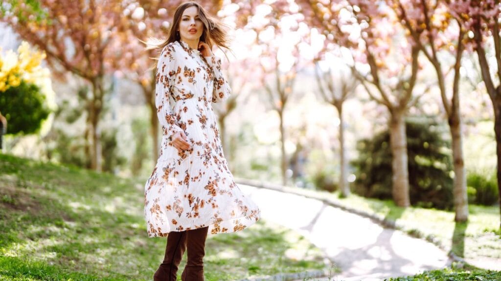 Woman wearing a floral flowy midi dress standing outdoors under blooming cherry blossom trees