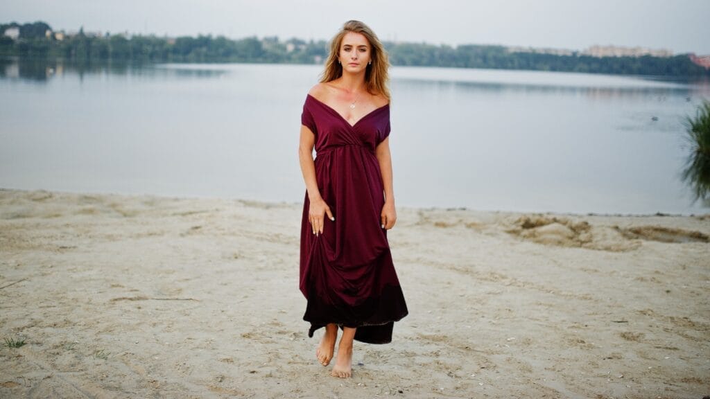 Woman in a mauve velvet dress standing by the water