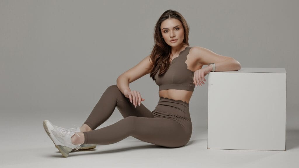 Woman sitting in a brown activewear set showcasing non-ribbed seamless leggings for fitness and athleisure style