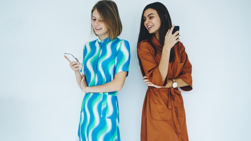 Two women wearing colorful short sleeve midi dresses casual, one with a blue and green pattern, and the other in a brown shade, both smiling