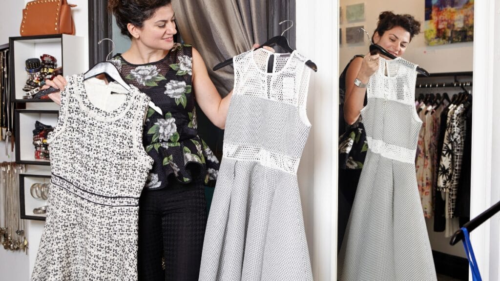 Woman choosing between two stylish dresses in a boutique