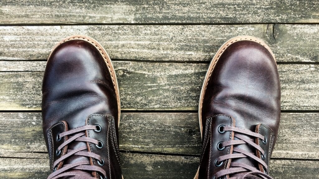 Close-up of stylish brown leather boots on a wooden surface.