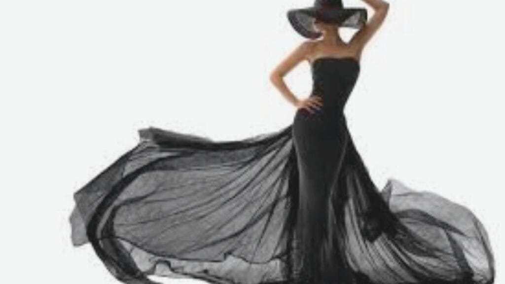 Woman wearing an elegant strapless black gown with a flowing train and a wide-brimmed black hat, striking a dramatic pose.