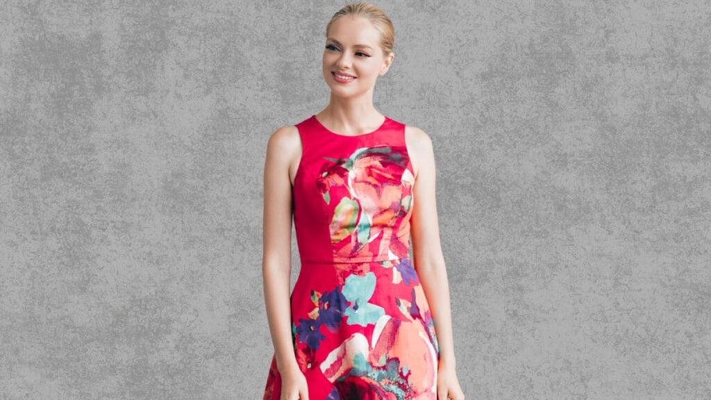 Elegant woman in a pink floral cocktail dress, size 14, posing gracefully against a gray background
