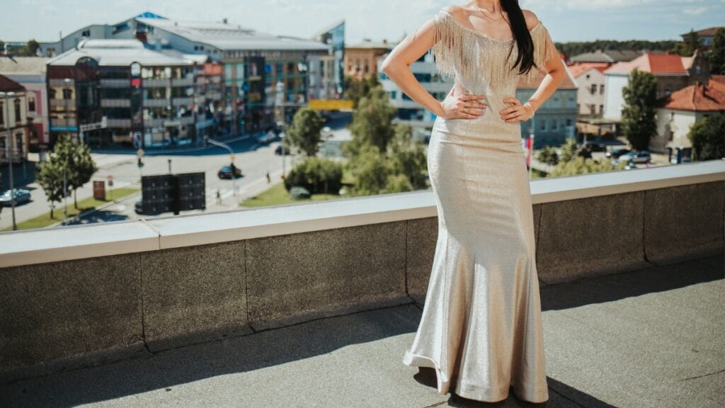 Bride in a flowing white gown, standing on a beach at sunset