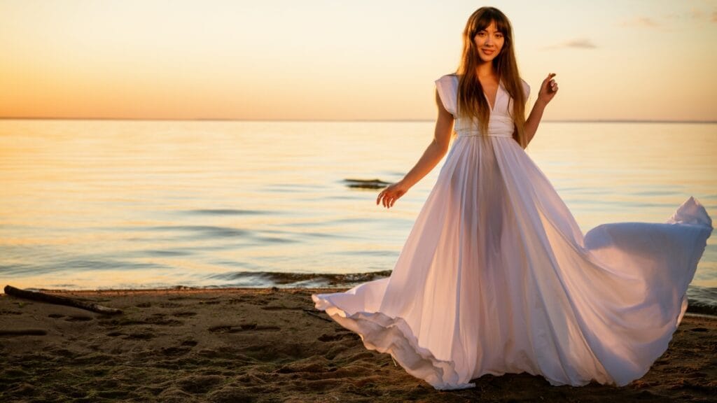 Elegant woman wearing a unique gown with fringe detailing, standing on a rooftop with city views
