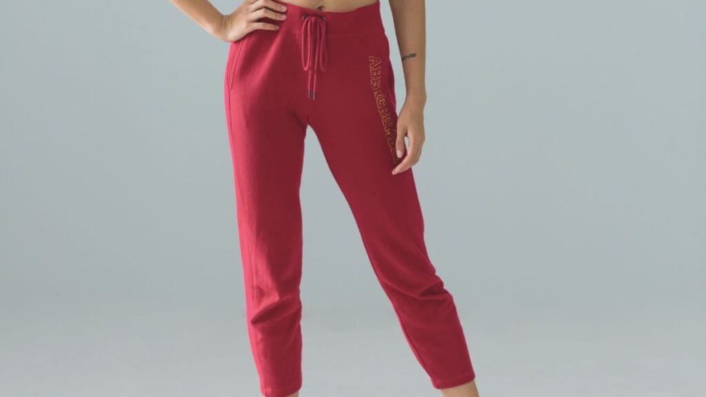 A woman wearing red jogger pants with a drawstring waist, posing confidently with one hand on her hip.