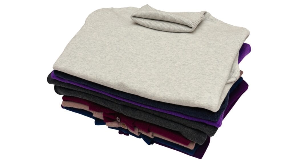 A stack of plus size sweaters in various colors, including grey, purple, and burgundy
