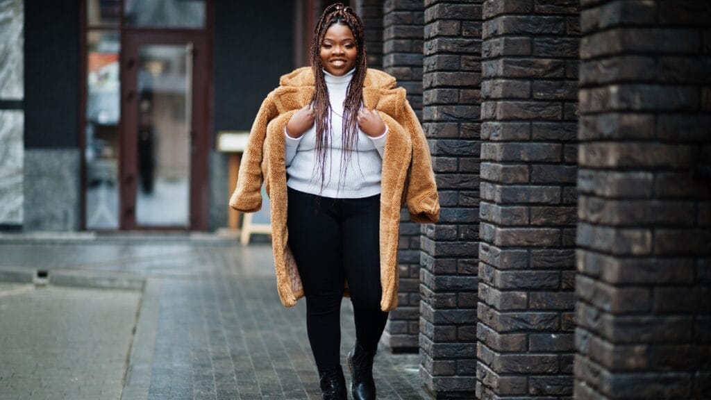 Happy plus-size woman smiling and wearing a brown winter coat on a chilly day