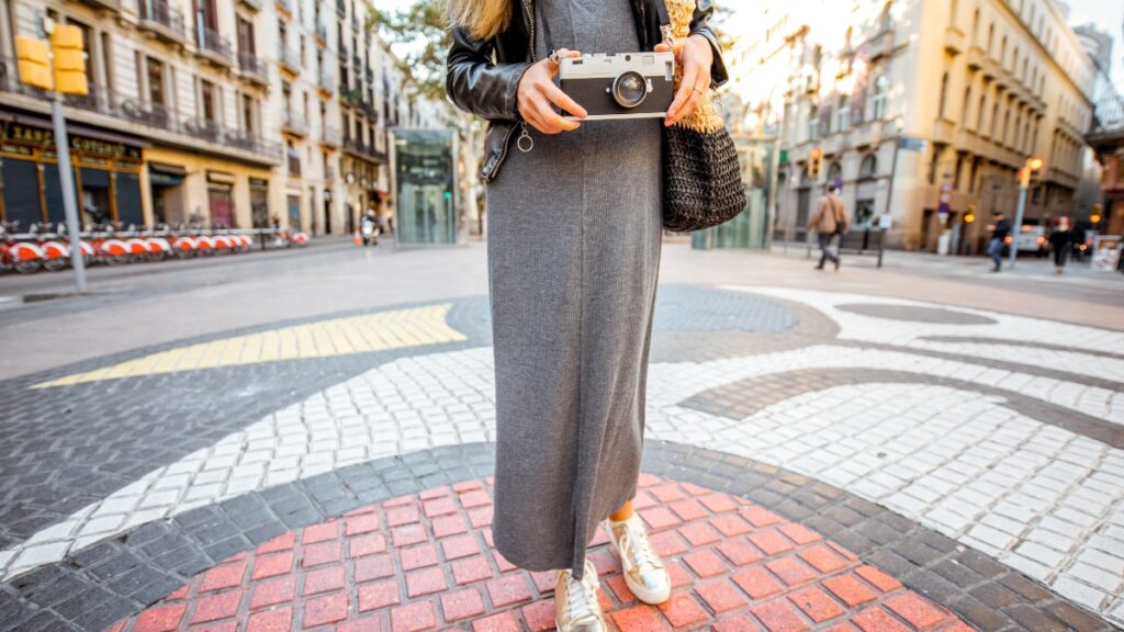 Woman in a casual long sleeve midi dress, paired with sneakers for a modern look.