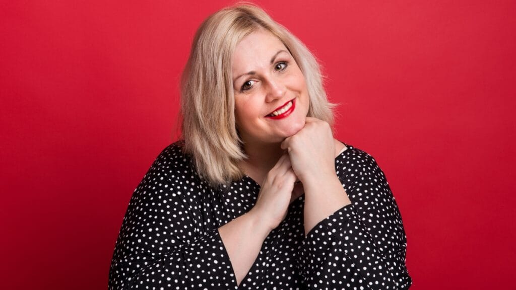 Plus-size woman smiling in black and white polka dot dress, perfect for mother of bride plus size fashion