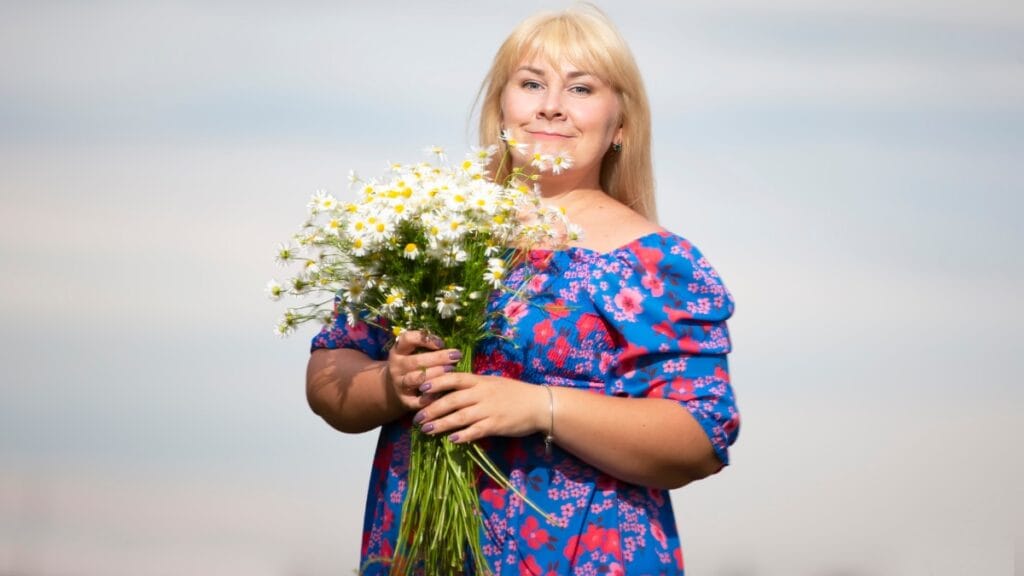 Mother of bride plus size holding a bouquet of daisies in a floral dress