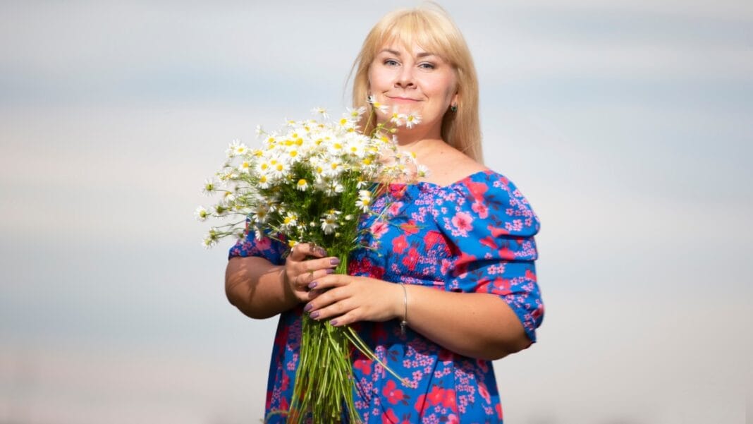 Mother of bride plus size holding a bouquet of daisies in a floral dress