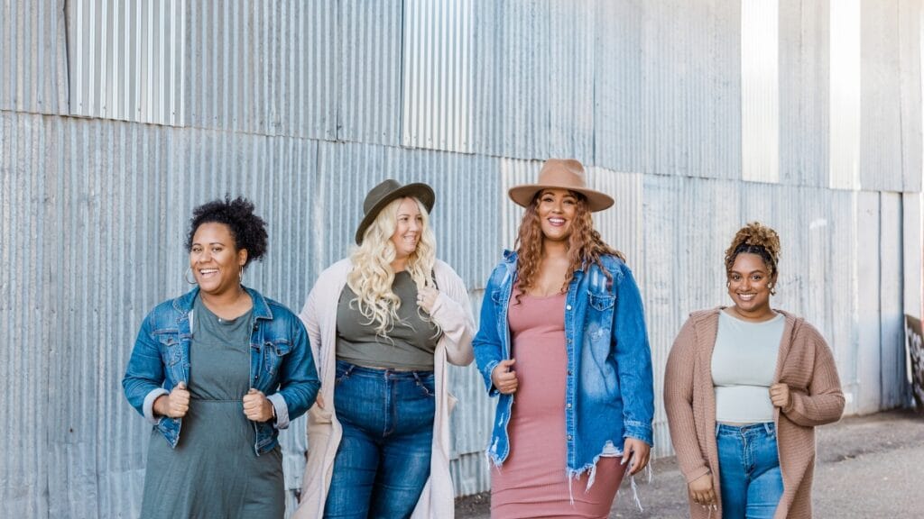 Four women wearing trendy plus-size fashion, showing different styles with denim jackets and hats