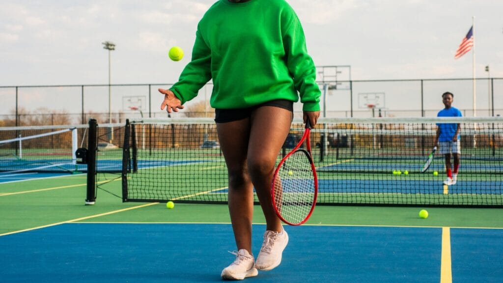 Plus-size woman playing tennis on an outdoor court, wearing tennis gear