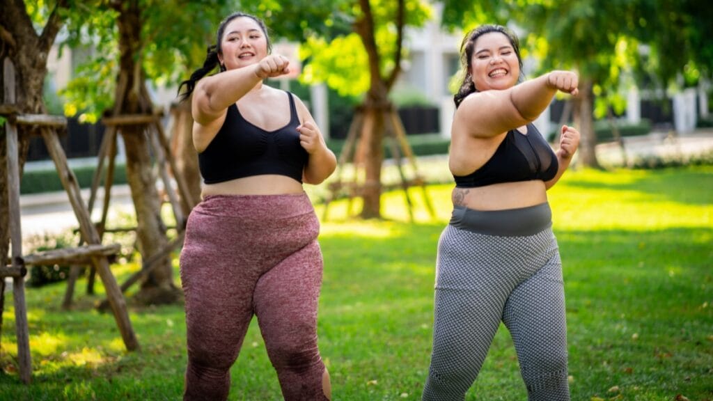 Plus size women in vibrant activewear, wearing colorful track pants while exercising outdoors.