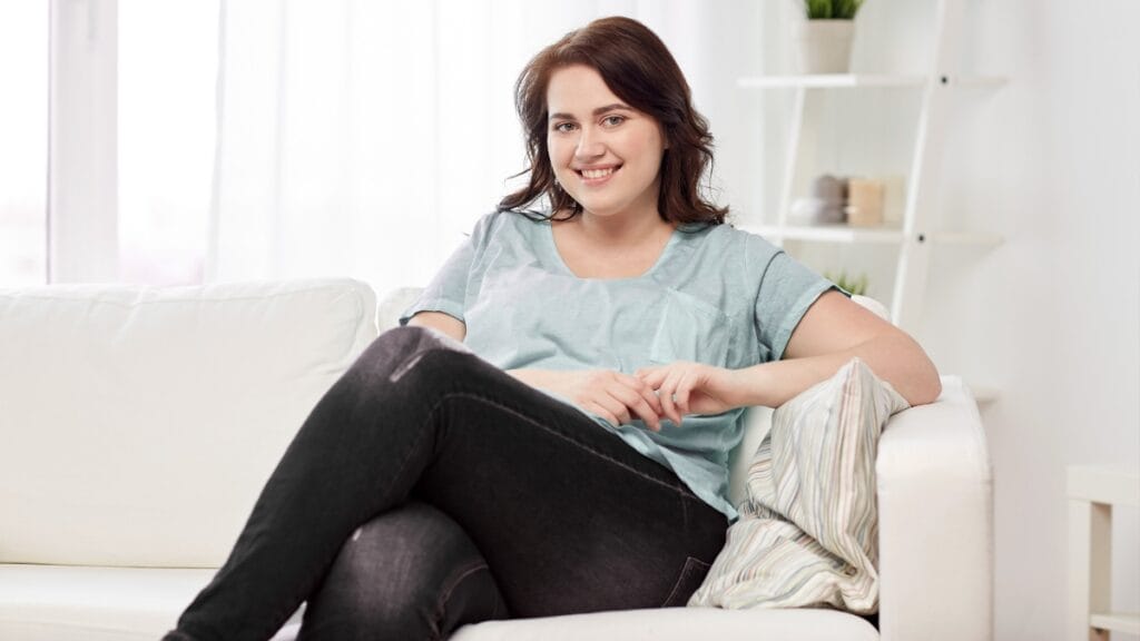 Plus size woman sitting on a sofa in comfortable black sweatpants, looking relaxed and confident